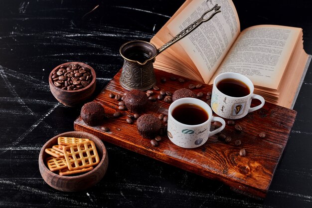 Een kopje koffie met chocoladepralines en koekjes.