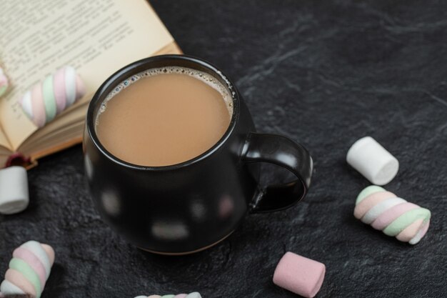 Een kopje koffie met marshmallows en boek.