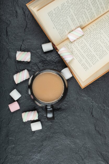 Een kopje koffie met marshmallows en boek.