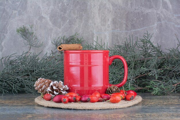 Een kopje koffie met rozenbottels en dennenappels op marmeren achtergrond. Hoge kwaliteit foto