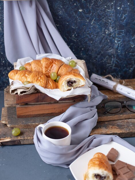 Een kopje melkachtige cappuccino met een koekje op de blauwe tafel.