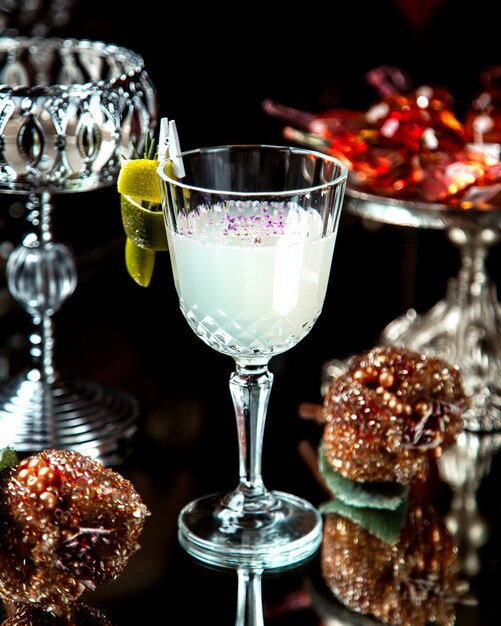 Een kristalglas met witte cocktail gegarneerd met citroenschil