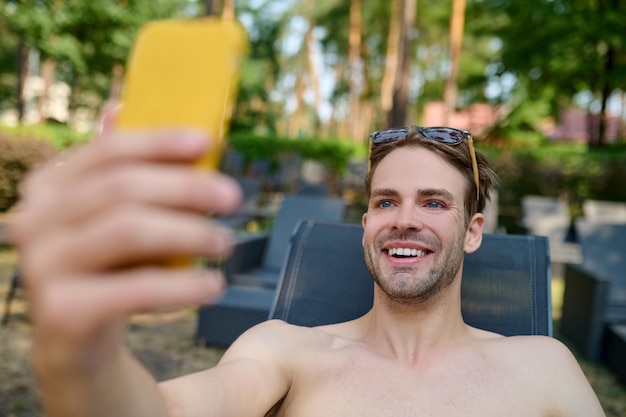 Een lachende man die selfie maakt en er opgewonden uitziet