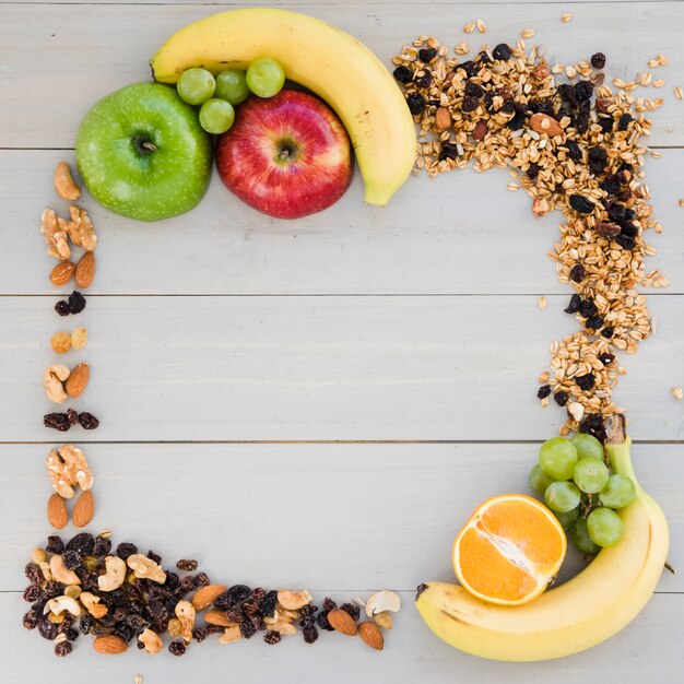 Een leeg frame gemaakt met gedroogde vruchten; haver en fruit op houten bureau