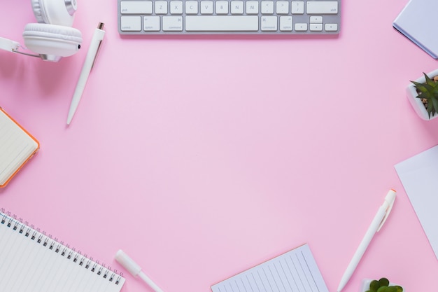 Een lege ruimte voor het schrijven van tekst en kantoorbenodigdheden tegen roze achtergrond