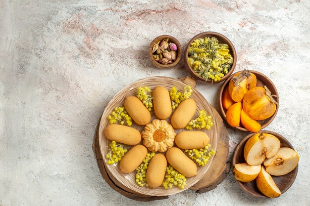 Een luchtfoto van koekjes en schalen met droge bloemen en fruit staan erop op marmeren grond