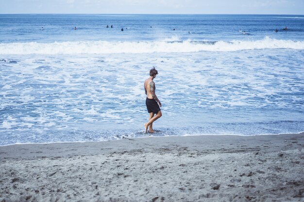 een man aan de kust van de oceaan loopt langs de kust