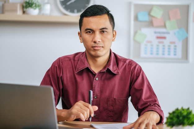 Een man aan het werk op kantoor met papieren en laptop op bureau