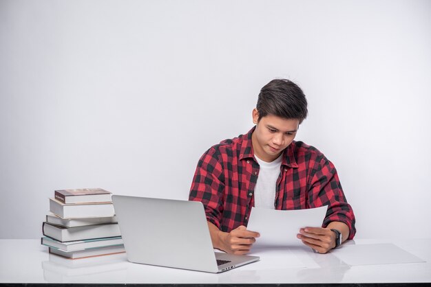 Een man die een laptop op kantoor gebruikt en een documentanalyse doet.