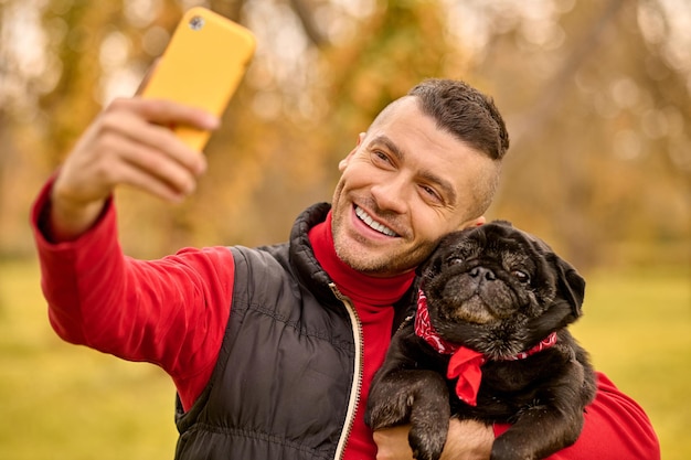 Een man die zijn hond knuffelt en selfie maakt