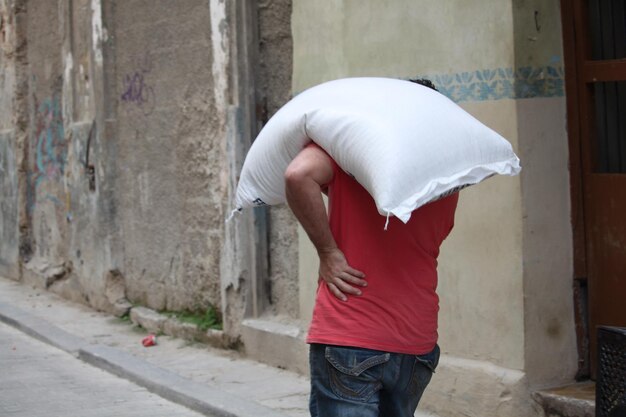 Een man draagt een zak vertegenwoordigt het gewicht van het leven op de schouders van een persoon