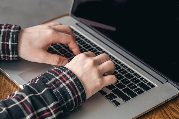 Een man drukt op de toetsen van een laptop close-up