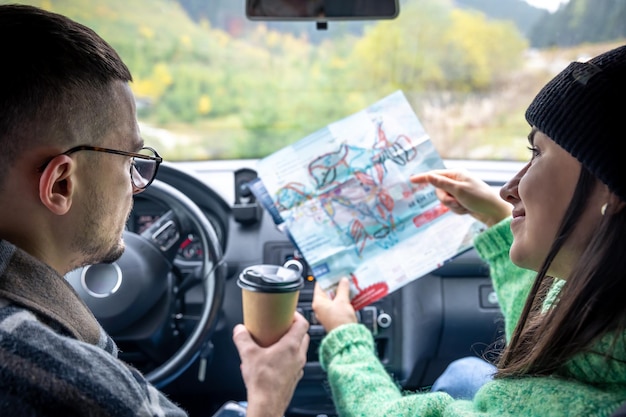 Gratis foto een man en een dame die een papieren kaart vasthouden en bekijken die in de auto zit