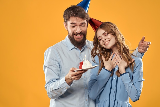 Een man en een vrouw op een verjaardag met een cupcake en een kaars in een feestelijke pet hebben plezier en vieren de vakantie samen