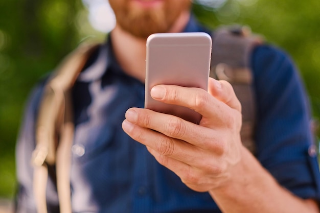 Een man houdt een zilveren smartphone vast. Detailopname.