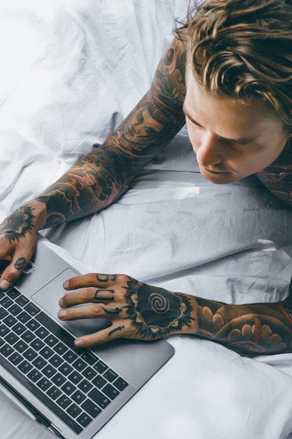een man in bed werkt op een laptop, post controleren, een film kijken, naar muziek luisteren