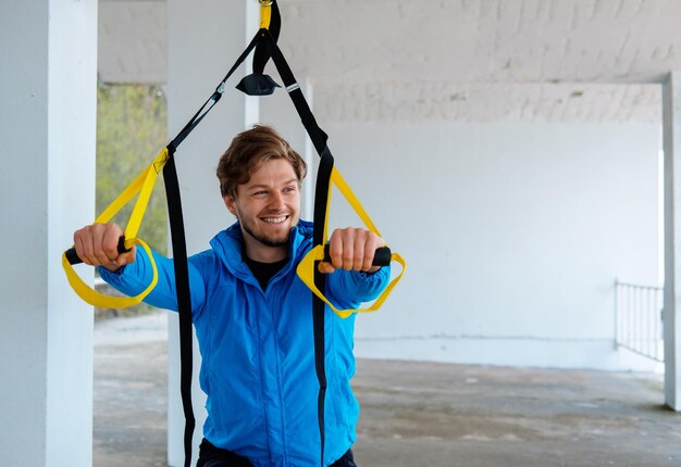 Een man in een park die de flexibiliteit van zijn benen verbetert met fitness trx-strips.