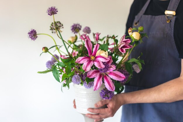 Een man in een schort houdt een vaas met bloemen close-up