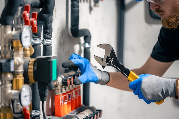 Een man installeert een verwarmingssysteem in een huis en controleert de leidingen met een moersleutel