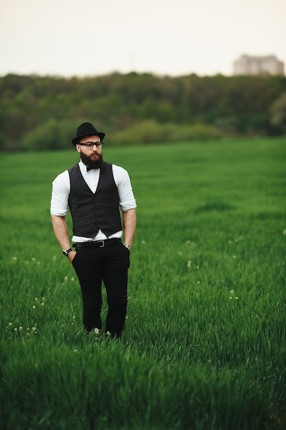 Een man met een baard en zonnebril die op het veld loopt