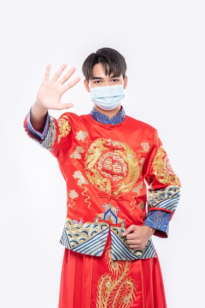 Een man met een cheongsam en een masker laat zien dat mensen die geen maskers dragen tijdens het nieuwe maanjaar niet kunnen winkelen.