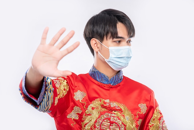 Een man met een cheongsam en een masker laat zien dat mensen die geen maskers dragen tijdens het nieuwe maanjaar niet kunnen winkelen.