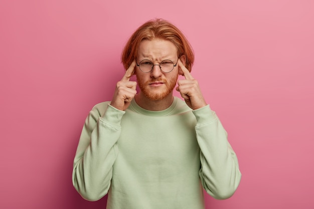 Een man met een intense baard raakt de slapen met beide wijsvingers aan