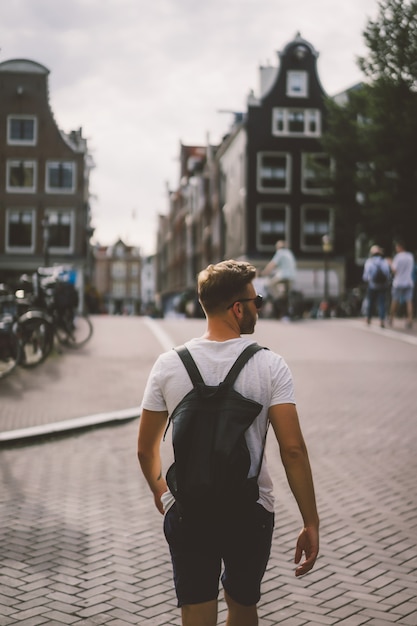 Een man met een rugzak loopt door de straten van Amsterdam.