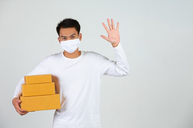 Een man met een wit t-shirt houdt een bruine brievenbus vast om dingen te bezorgen. Maak gebaren en gezichtsuitdrukkingen.