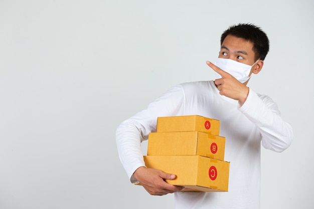 Een man met een wit t-shirt houdt een bruine brievenbus vast om dingen te bezorgen. Maak gebaren en gezichtsuitdrukkingen.