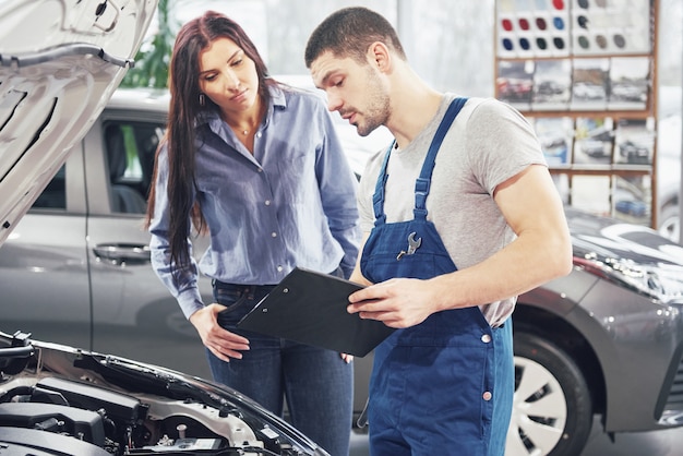 Een man monteur en vrouw klant bespreken reparaties aan haar voertuig