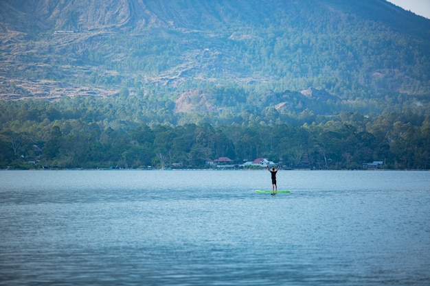 Een man op het meer rijdt op een sup board.