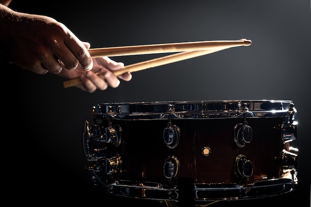 Een man speelt met stokken op een trommel, een drummer speelt een percussie-instrument, kopieer ruimte.