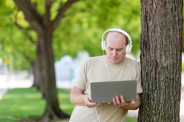 een man werkt op een laptop in het park