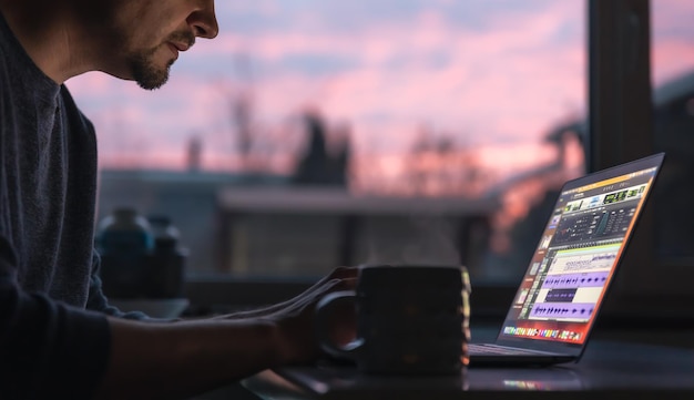 Een man werkt 's ochtends vroeg met geluid op een laptop