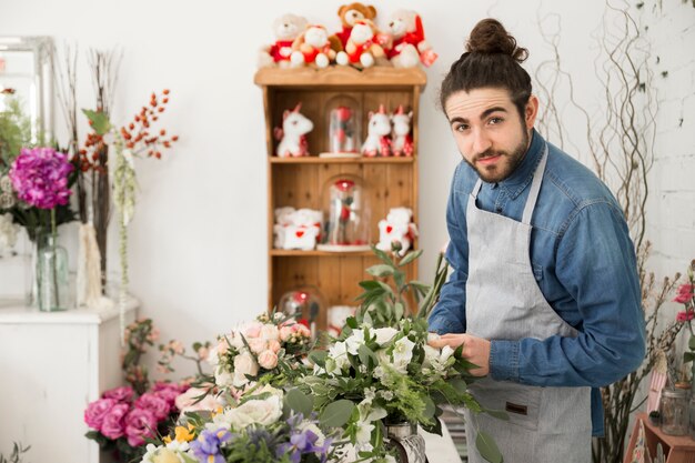 Een mannelijke bloemist die het bloemboeket in zijn winkel maakt