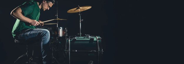 Een mannelijke drummer speelt een drumstel op een zwarte achtergrond kopie ruimte