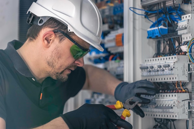 Gratis foto een mannelijke elektricien werkt in een schakelbord met behulp van een elektrische aansluitkabel