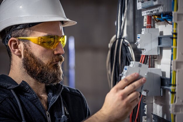 Een mannelijke elektricien werkt in een schakelbord met een elektrische verbindingskabel