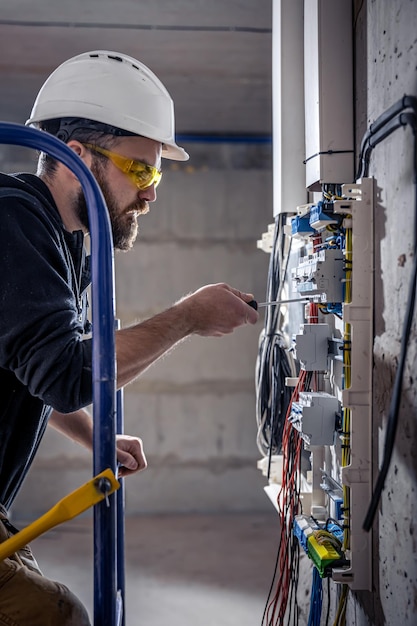 Een mannelijke elektricien werkt in een schakelbord met een elektrische verbindingskabel