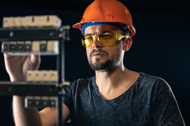 Een mannelijke elektricien werkt in een schakelbord met een elektrische verbindingskabel