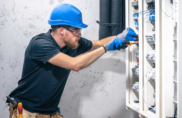 Gratis foto een mannelijke elektricien werkt in een schakelbord met een elektrische verbindingskabel