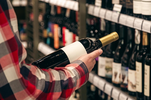 Gratis foto een mannelijke klant die een fles rode wijn van dichtbij vasthoudt