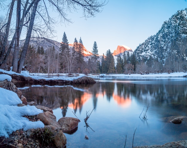 Een meer omgeven door rotsen, bomen en bergen in Yosemite in de winter