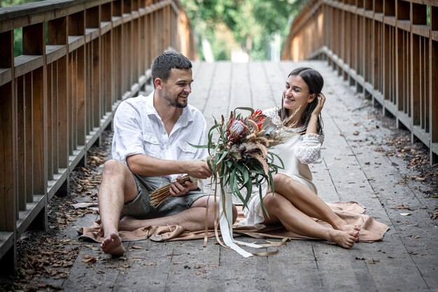 Een meisje en een jonge man zitten op de brug en genieten van communicatie, een date in de natuur, een liefdesverhaal.