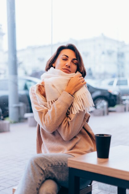 Een meisje in een gezellig café warmt zichzelf op met een kop warme koffie