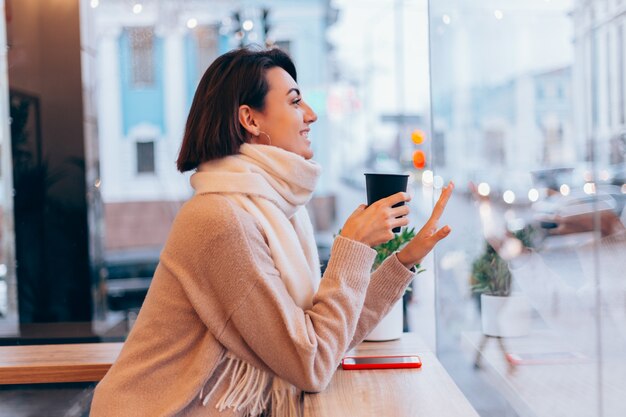 Een meisje in een gezellig café warmt zichzelf op met een kop warme koffie