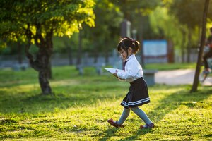 Een meisje speelt met een papieren vliegtuigje in het park