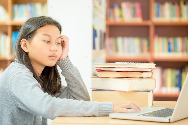 een meisje zit om een boek in de bibliotheek te lezen