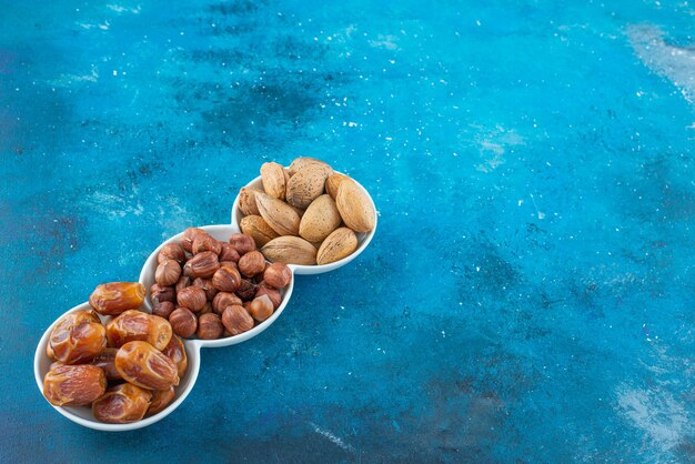 Een mix van noten in een kom, op de blauwe tafel.